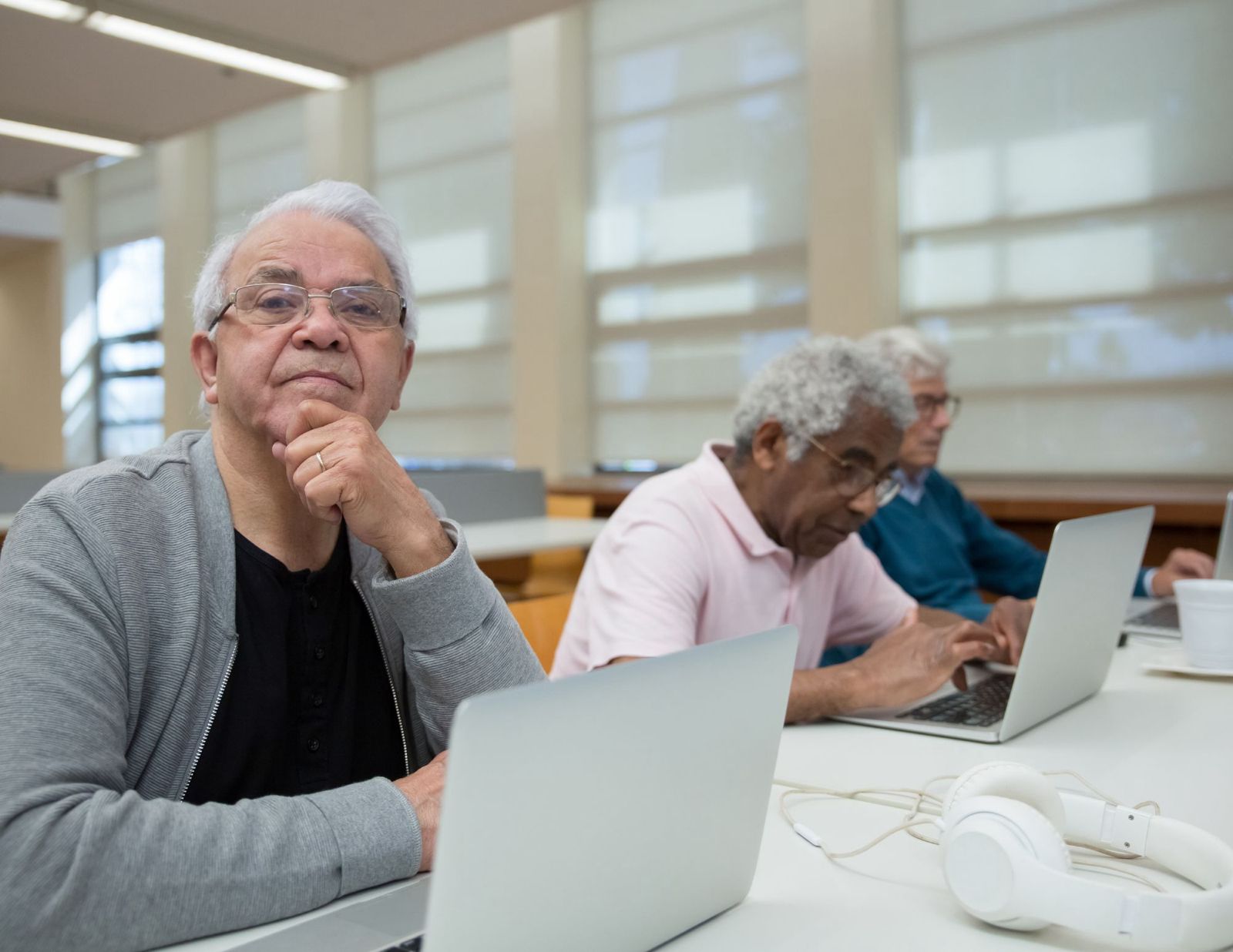 Senior adults learning to use laptops in a bright library classroom